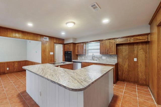 kitchen with a spacious island, sink, light tile patterned floors, wooden walls, and black appliances