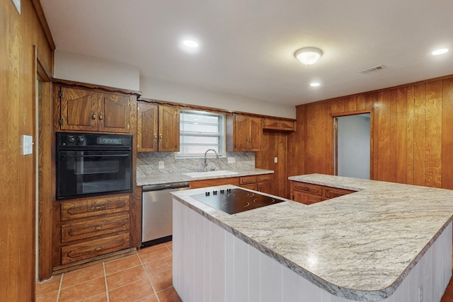 kitchen featuring sink, backsplash, black appliances, and a kitchen island