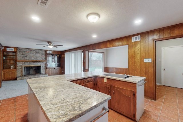 kitchen with black electric stovetop, a fireplace, a kitchen island, and wood walls