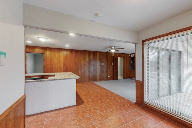 kitchen with light tile patterned floors, plenty of natural light, wooden walls, and ceiling fan