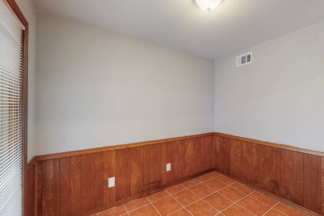 tiled empty room featuring wood walls