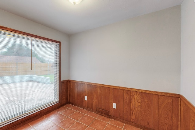 tiled empty room featuring wooden walls