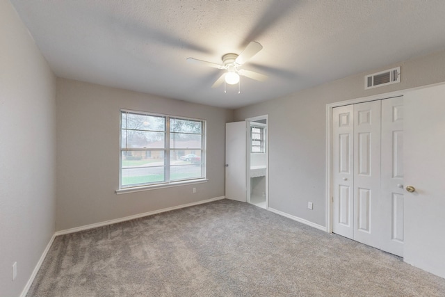 unfurnished bedroom with light carpet, ceiling fan, a closet, and a textured ceiling