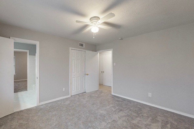 unfurnished bedroom featuring a textured ceiling, light colored carpet, a closet, and ceiling fan