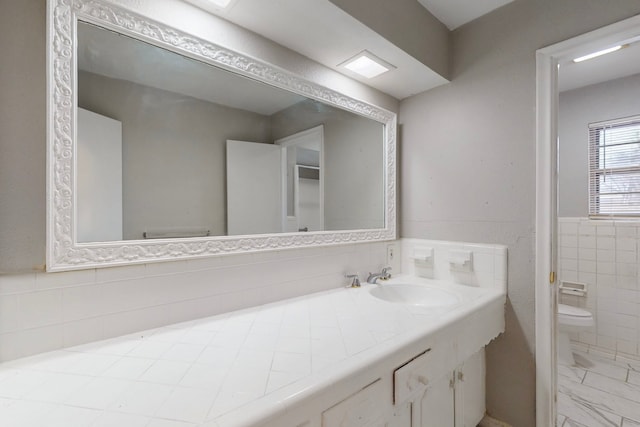 bathroom with tile walls, vanity, and toilet