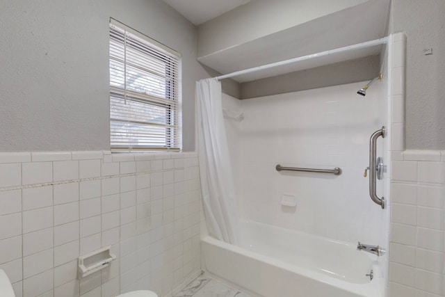 bathroom with tile walls, toilet, and shower / bath combo with shower curtain