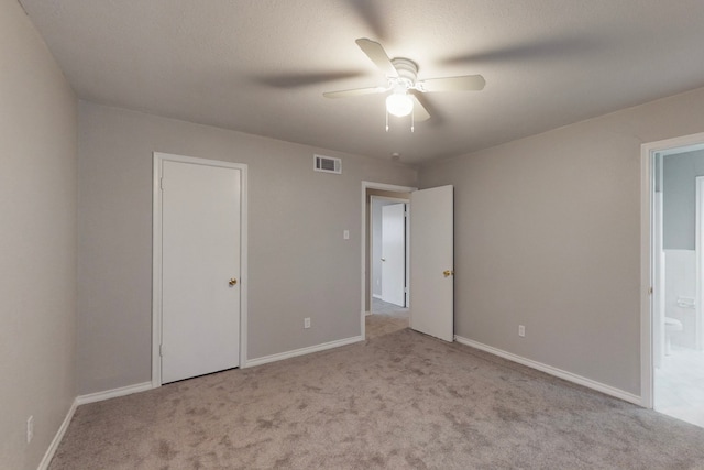 unfurnished bedroom with ensuite bath, light colored carpet, and ceiling fan