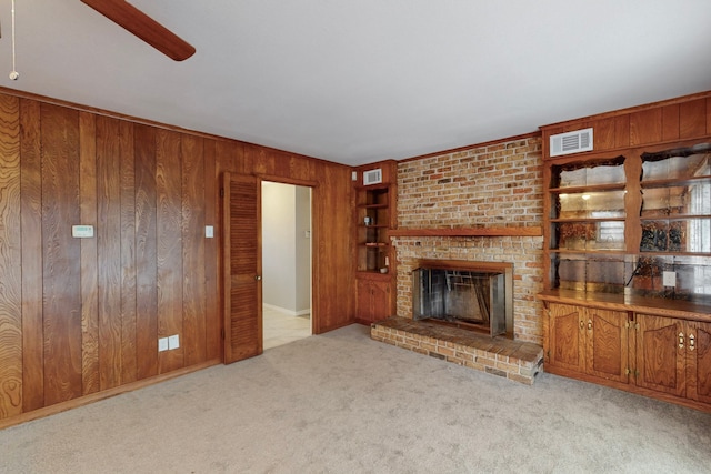 unfurnished living room with a fireplace, light carpet, and wood walls