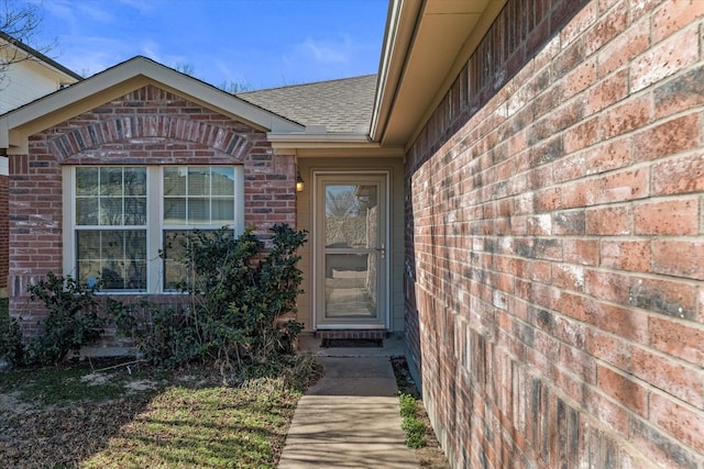 entrance to property with brick siding and roof with shingles