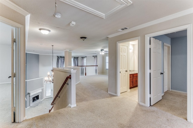 corridor featuring light carpet, crown molding, and a chandelier