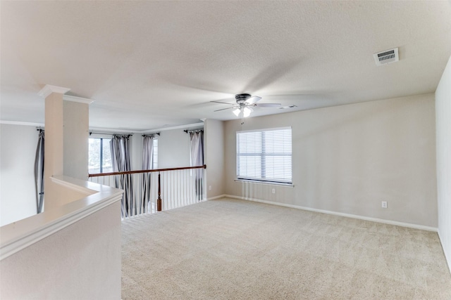 carpeted spare room featuring ornate columns, ceiling fan, a textured ceiling, and ornamental molding