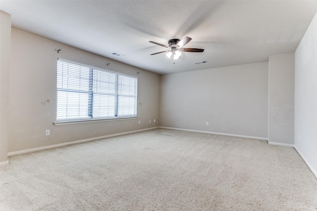 unfurnished room featuring ceiling fan, light carpet, and a textured ceiling