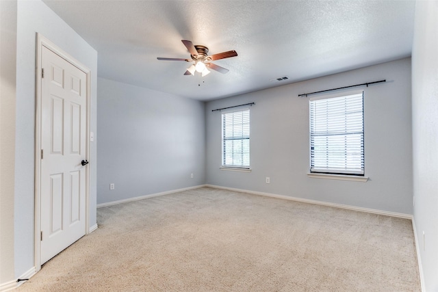 carpeted spare room with ceiling fan and a textured ceiling