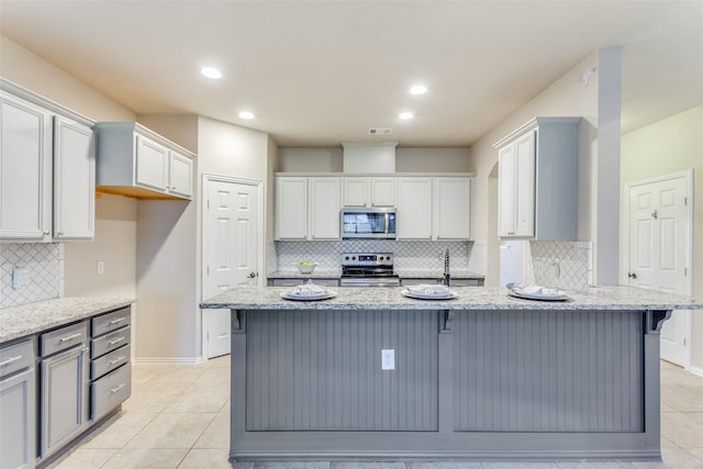 kitchen featuring appliances with stainless steel finishes, gray cabinets, light stone countertops, and light tile patterned floors