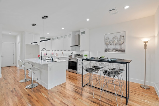 kitchen featuring hanging light fixtures, a kitchen island with sink, white cabinets, and electric range