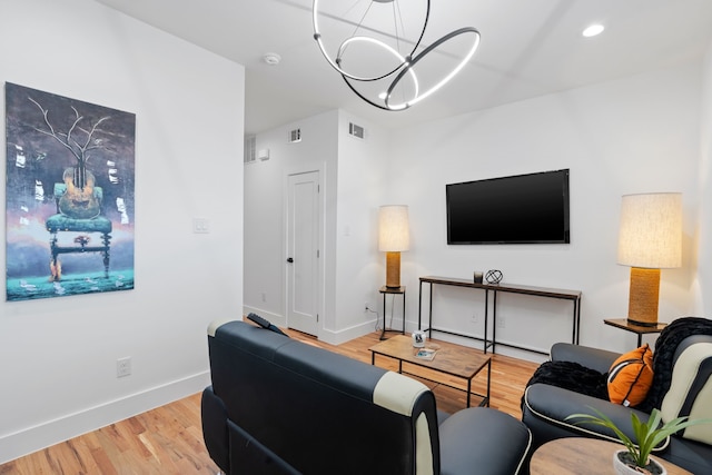 living room with an inviting chandelier and light hardwood / wood-style floors