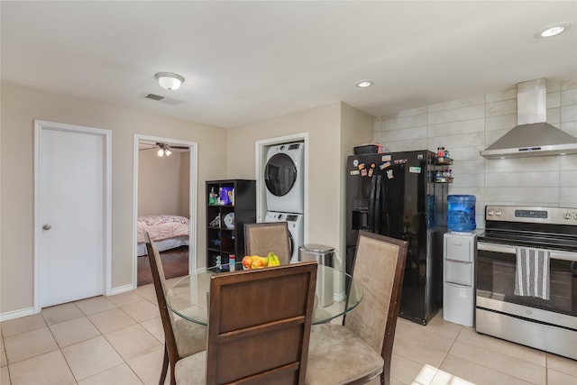 tiled dining area featuring ceiling fan and stacked washer / dryer