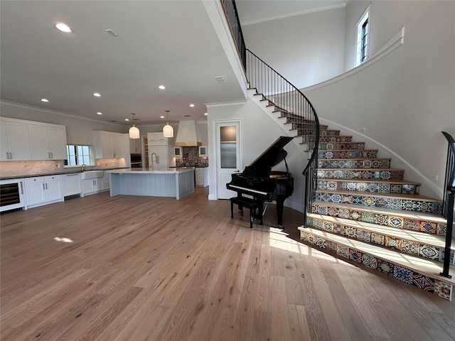 interior space with wine cooler, ornamental molding, and light hardwood / wood-style flooring