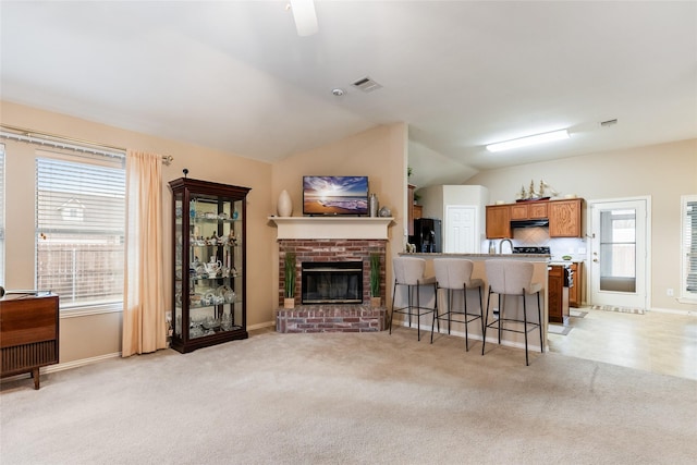 carpeted living room featuring lofted ceiling and a brick fireplace