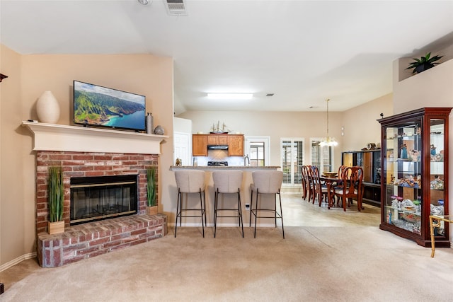 carpeted living room featuring lofted ceiling, a fireplace, and a chandelier