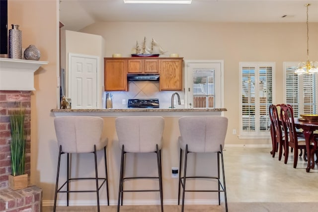 kitchen featuring range, decorative light fixtures, a notable chandelier, light stone countertops, and backsplash