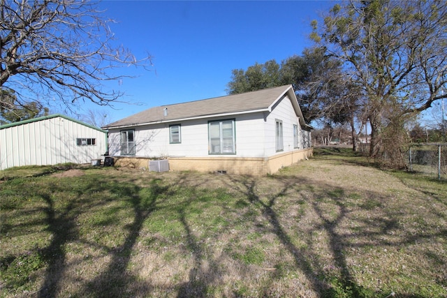 rear view of house featuring brick siding, a lawn, cooling unit, and fence