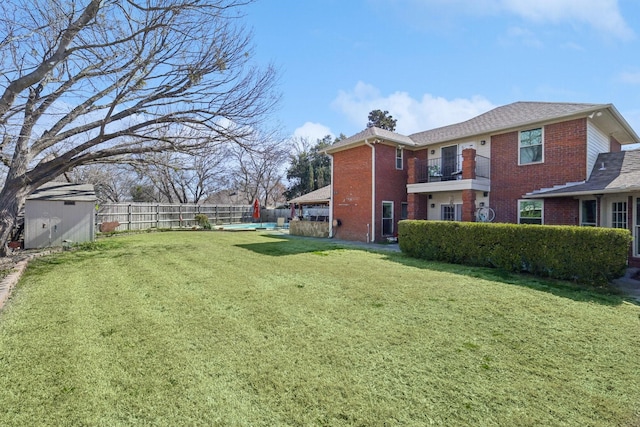 view of yard featuring an outbuilding, a balcony, a storage unit, and a fenced backyard