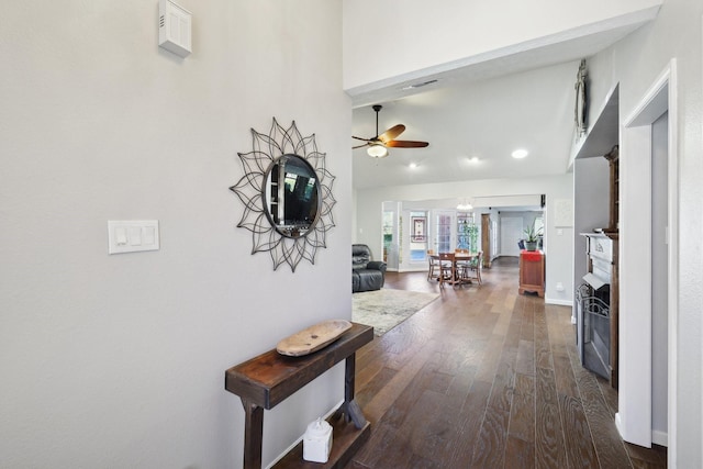 corridor featuring visible vents, baseboards, dark wood-type flooring, and a towering ceiling