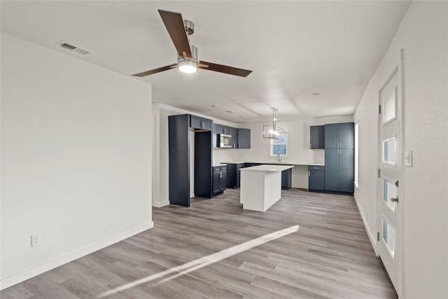 kitchen featuring a center island, ceiling fan with notable chandelier, and light hardwood / wood-style flooring