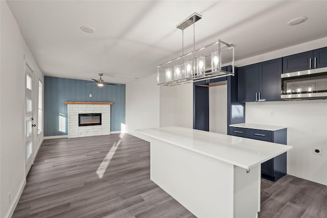 kitchen featuring hanging light fixtures, dark wood-type flooring, ceiling fan, and a kitchen bar