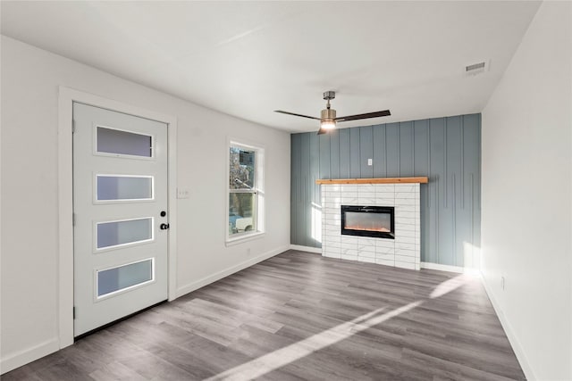 unfurnished living room featuring hardwood / wood-style flooring, ceiling fan, and a tiled fireplace