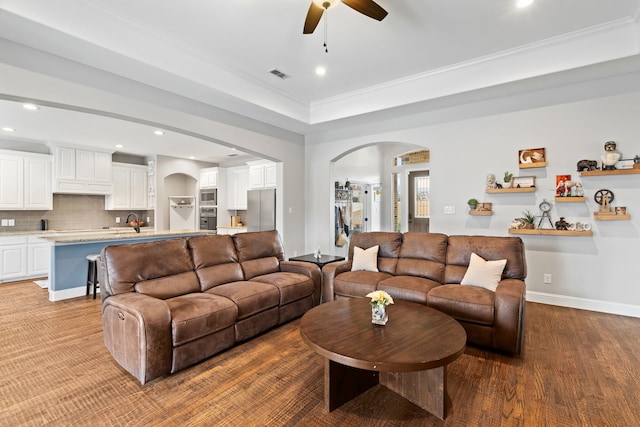 living room featuring crown molding, ceiling fan, wood-type flooring, and a tray ceiling