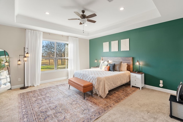 bedroom with ceiling fan, a tray ceiling, and carpet