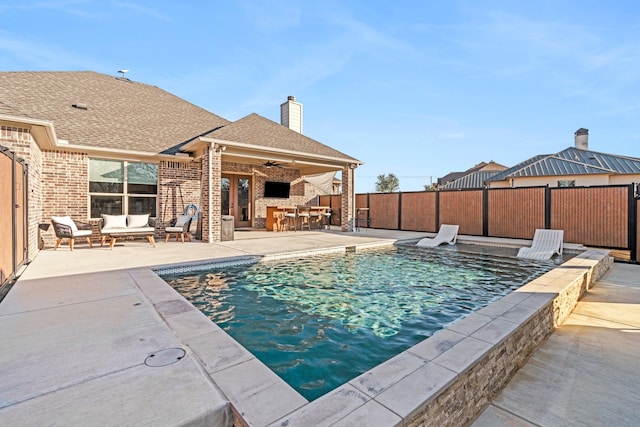 view of swimming pool featuring a patio area, outdoor lounge area, ceiling fan, and exterior bar