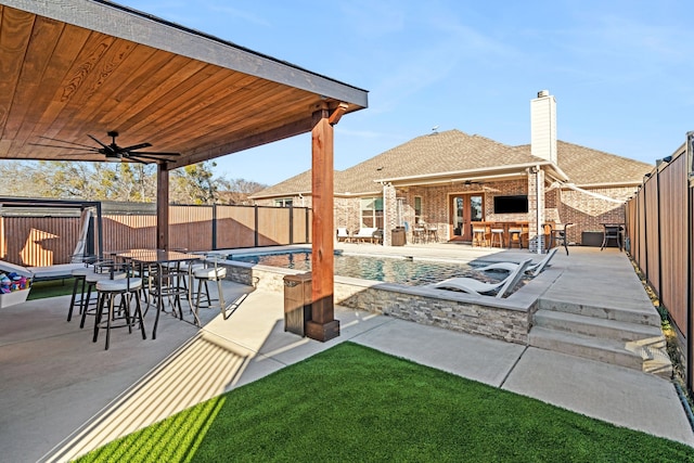 view of patio / terrace featuring a fenced in pool, exterior bar, and ceiling fan