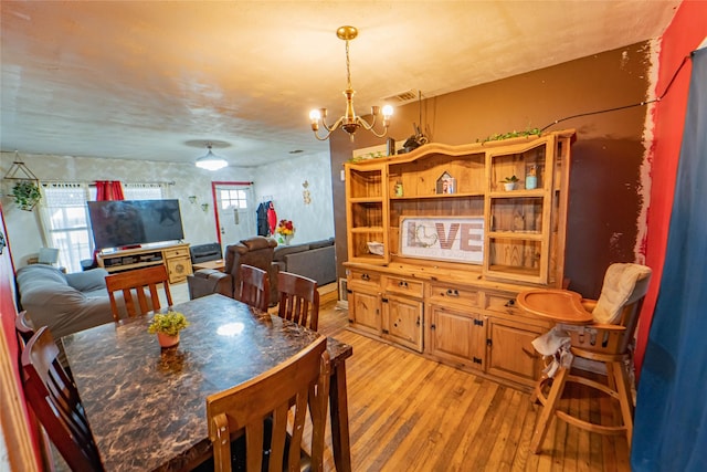 dining space featuring light hardwood / wood-style flooring and a chandelier