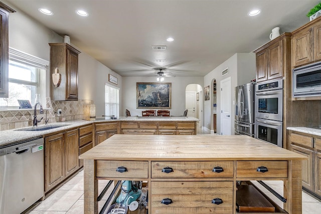 kitchen featuring visible vents, a sink, backsplash, stainless steel appliances, and a healthy amount of sunlight