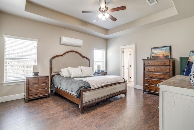 bedroom with dark wood-style floors, visible vents, and a tray ceiling