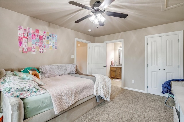 bedroom with a ceiling fan, baseboards, a closet, light colored carpet, and connected bathroom