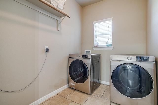 laundry room featuring laundry area, light tile patterned floors, washing machine and dryer, and baseboards