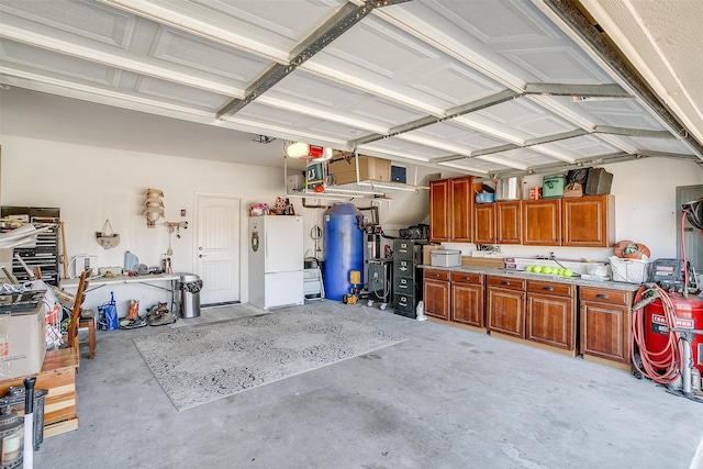 garage featuring gas water heater, a workshop area, and freestanding refrigerator