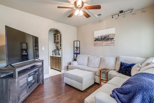 living room with visible vents, ceiling fan, rail lighting, wood finished floors, and arched walkways