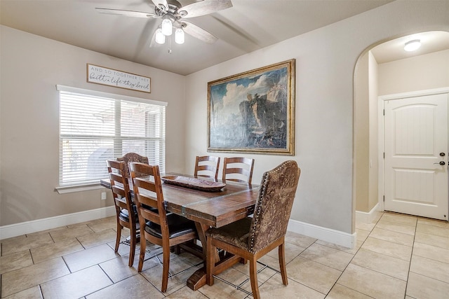 dining room featuring light tile patterned floors, arched walkways, and baseboards