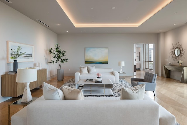 living room with a tray ceiling, baseboards, and visible vents