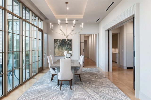 dining space with visible vents, baseboards, a tray ceiling, and a notable chandelier