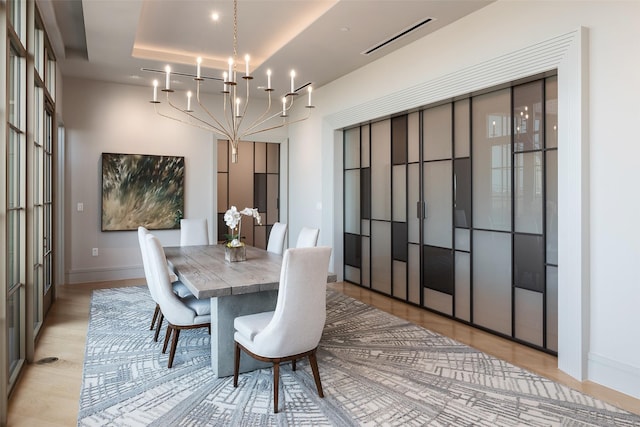 dining space featuring light wood finished floors, an inviting chandelier, baseboards, and visible vents