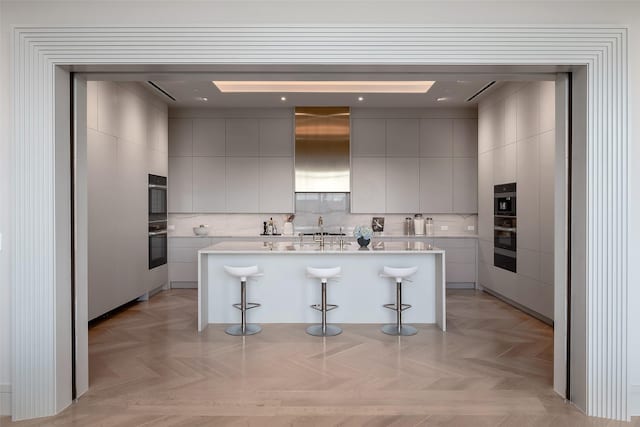 kitchen featuring light countertops, a kitchen island, a breakfast bar area, and modern cabinets