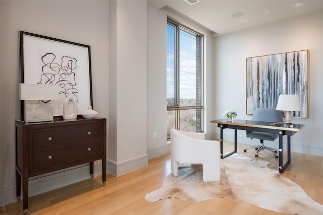 office area with light wood-type flooring, baseboards, and a healthy amount of sunlight
