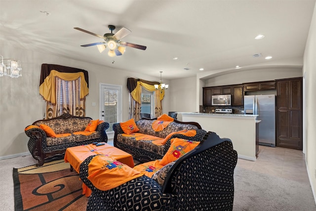 living room with ceiling fan with notable chandelier and light colored carpet