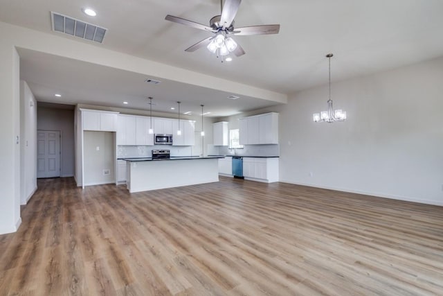 unfurnished living room featuring ceiling fan with notable chandelier and light wood-type flooring